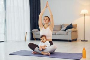 Doing yoga exercises. Mother with her little daughter is at home together photo
