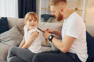 en el sofá. divirtiéndose. padre con su pequeña hija está en casa juntos foto