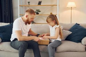 con caja de regalo. padre con su pequeña hija está en casa juntos foto