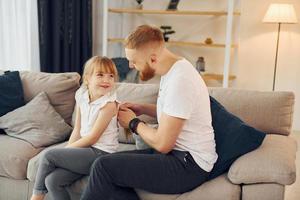 el hombre trenza las trenzas. padre con su pequeña hija está en casa juntos foto