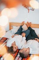 acostada en la cama. Encantadora pareja celebrando las vacaciones juntos en el interior foto