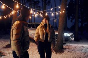 Automobile parked behind. Couple standing in the forest and celebrating New year photo