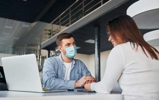 la mujer recibe ayuda del trabajador. joven con camisa blanca y chaqueta azul está adentro foto