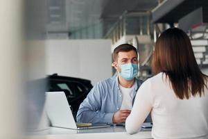 Woman receive help by worker. Young man in white shirt and blue jacket is indoors photo