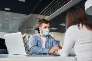 Woman receive help by worker. Young man in white shirt and blue jacket is indoors photo