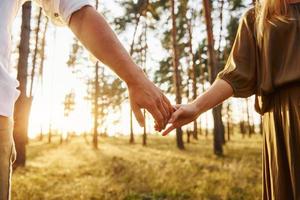 Close up view of hands. Happy couple is outdoors in the forest at daytime photo