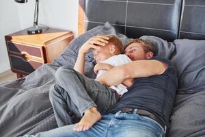 Laying down on the bed. Father and son is indoors at home together photo