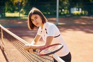 Near the net. Female tennis player is on the court at daytime photo