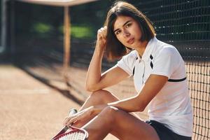 mirando a la cámara. la tenista femenina está en la cancha durante el día foto