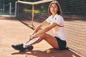 Looking at the camera. Female tennis player is on the court at daytime photo