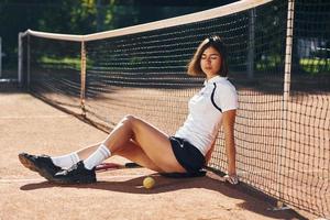 vista lateral. la tenista femenina está en la cancha durante el día foto