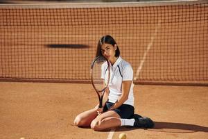 In black skirt. Female tennis player is on the court at daytime photo