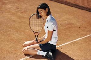In black skirt. Female tennis player is on the court at daytime photo