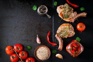 Grilled juicy steak on the bone with vegetables on a dark background. Top view photo