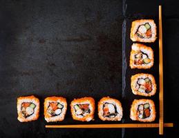 Traditional Japanese food - sushi, rolls and chopsticks for sushi on a dark background. Top view photo