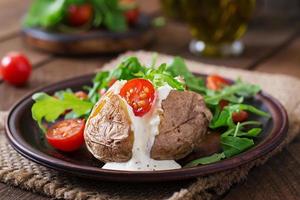 Baked potato filled with sour cream, arugula and tomatoes photo