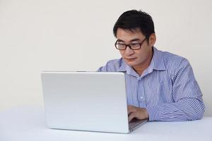 Handsome Asian man is working on laptop computer. Surfing internet. Concept. Online working, working with data. Technology in daily life photo