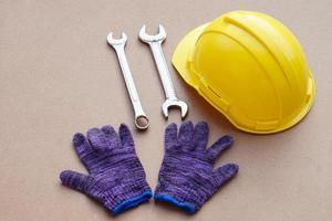 Yellow helmet, wrench and gloves. Concept, handyman or mechanic tools. Equipment for fixing or repairing, renovation in daily life. photo