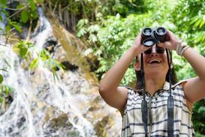 Girl using binoculars in forest photo