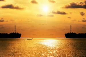 Silhouette high voltage electricity pylon at sunset over the sea photo