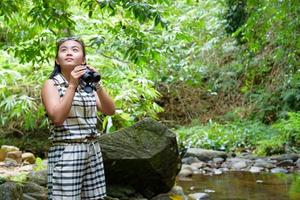 Girl using binoculars in forest photo