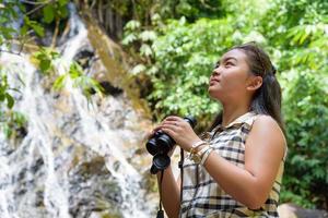 Girl using binoculars in forest photo