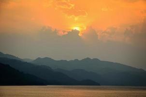 puesta de sol sobre una montaña en el lago foto