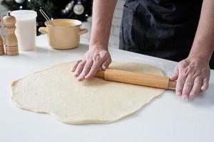 Male chef working with dough, cooking cinnamon rolls photo
