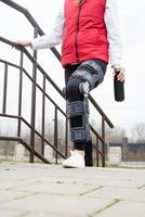 Woman wearing knee brace or orthosis after leg surgery, walking in the park photo