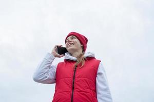 Woman wearing knee brace or orthosis after leg surgery walking in the park using smartphone photo