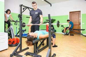 Instructor in gym while following people during exercises photo