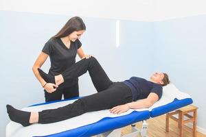 un fisioterapeuta realiza la movilización de las extremidades inferiores foto