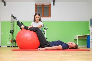 un fisioterapeuta realiza un ejercicio de tonificación muscular con el fitball.jpg foto