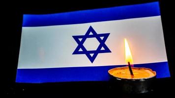 Israeli flag and candles burning in front of it, Holocaust memory day photo