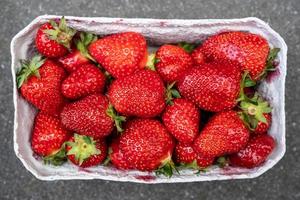 Delicious fragrant strawberries in a paper container. Red ripe berry is ready to eat. Top view. Close-up. photo