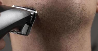 uomo rasatura il suo barba con un' taglio di capelli trimmer avvicinamento video