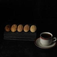 Kolombengi cake, and a cup of tea isolated on black background. Indonesian cake photo