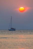 Sunset over the sea with boat silhouette photo