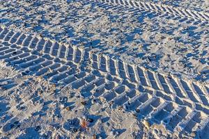 imagen de huellas de neumáticos en la arena de una playa durante el día foto