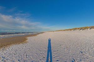 imagen de una larga sombra de una persona en una amplia playa de arena foto