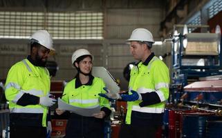 Young female engineer learning to run machinery at a factory with veteran engineers photo