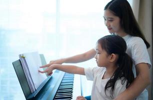 vacaciones familiares, otra hija ayudando a practicar en sus lecciones de piano foto