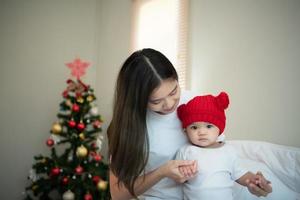 Mother and newborn baby wearing red hats In the white bedroom, warm sunlight in the evening of the day photo