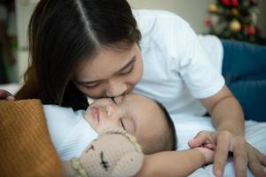 Young mother hugging her newborn child to lull the baby to sleep in the white bedroom photo