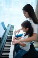 vacaciones familiares, otra hija ayudando a practicar en sus lecciones de piano foto