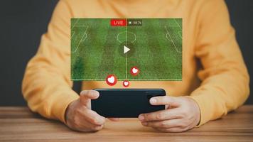 hombre que usa un teléfono inteligente o un teléfono móvil para ver fútbol en vivo en línea en una pantalla virtual, buscar videos en Internet, concepto de contenido en línea. foto