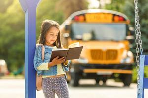 schoolgirl is waiting for a school bus photo