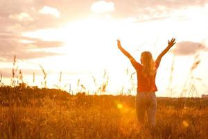 Woman silhouette waiting for summer sun on meadow photo