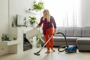 mujer joven con aspiradora en casa foto