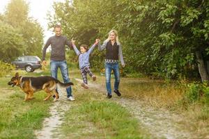 Happy children and parents with dog as family running in the nature photo